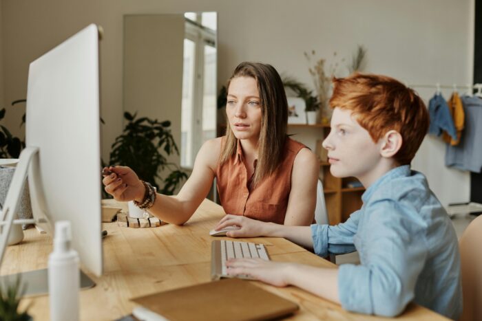 pexels-photo-4145354-4145354 A mother and her son attentively engaged in online learning at home on a computer.