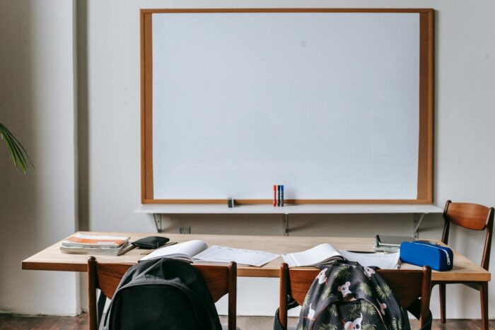 pexels-photo-5905441-5905441 Empty classroom with wooden desks, chairs, and a large whiteboard. Ideal for educational themes.